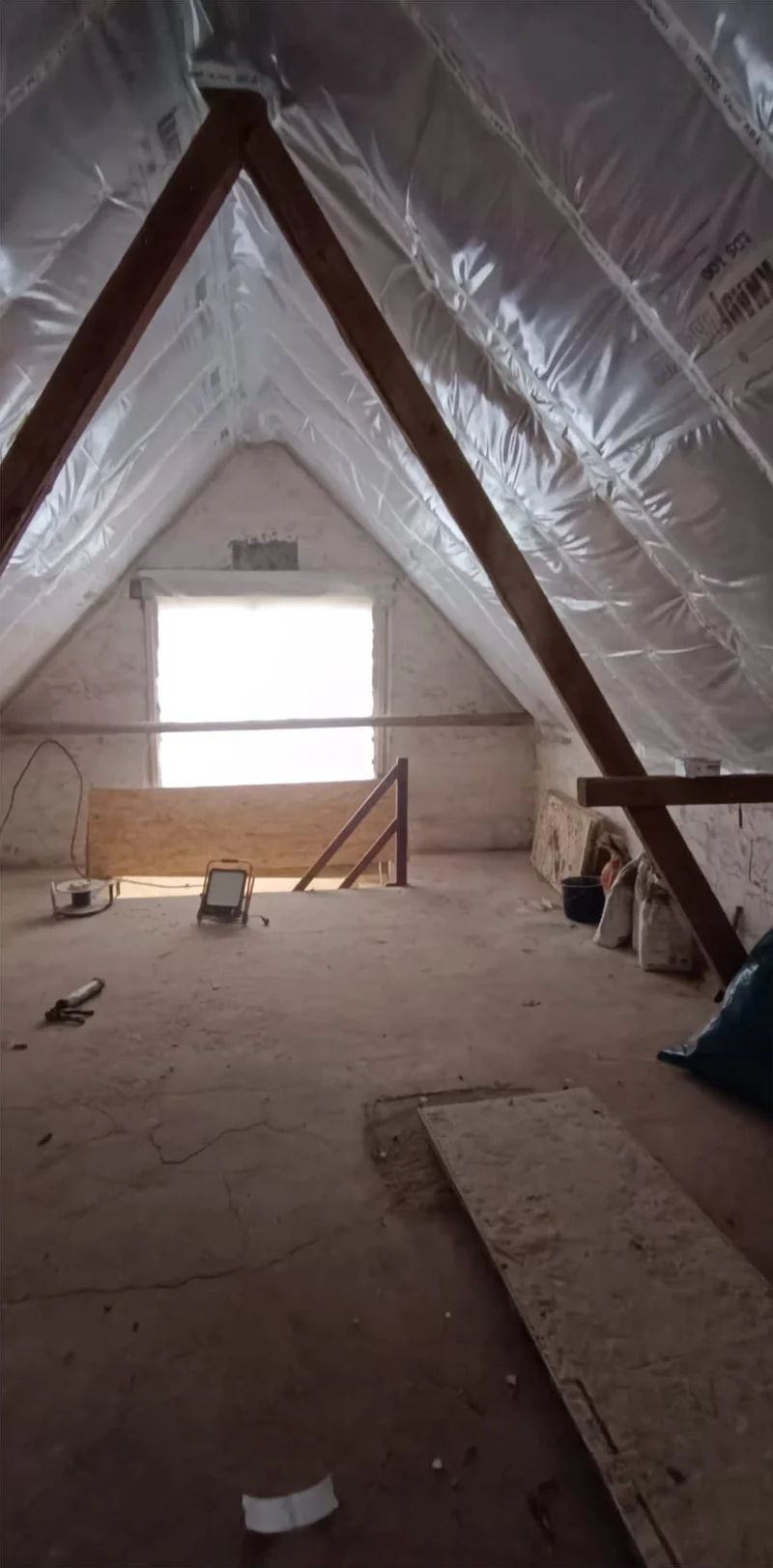 Dachgeschoss vor dem Ausbau mit sichtbarer Dämmfolie und Holzbalken